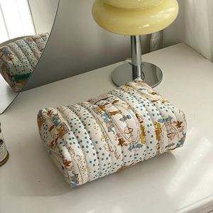 Detailed view of quilted cotton makeup bag with circus bear pattern on a white desk