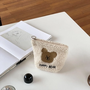 Close-up of cream fuzzy bear makeup pouch featuring soft texture and Happy Bear embroidery