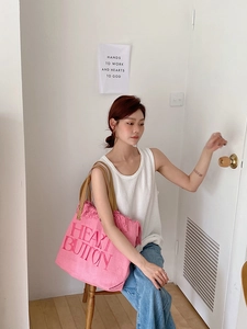 Detail of pink canvas tote bag with heart button embroidery and leather handles