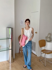 Pink fringe canvas tote bag paired with white ribbed tank top and wide-leg denim jeans