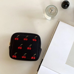 Détail de la pochette en tissu noir avec broderie de cerises rouges et zip doré