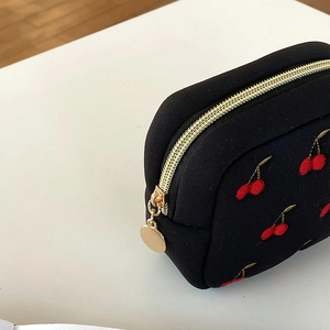 Gros plan d'une broderie cerise sur toile noire avec une fermeture dorée