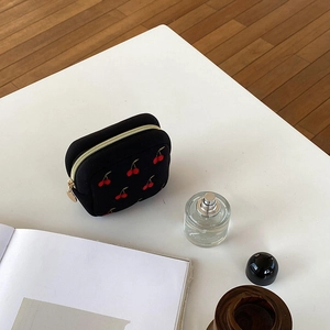 Détail d'une pochette à bijoux carrée noire avec broderie cerises et fermeture éclair dorée