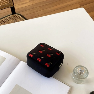 Vue détaillée de la pochette noire avec broderie cerise et fermeture dorée