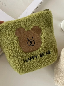 Detail of green fleece pouch with brown bear embroidery and Happy Bear text on soft fabric