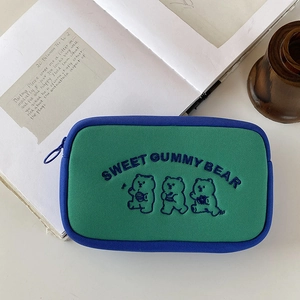 Close-up of green canvas storage bag featuring cute gummy bear embroidery and blue trim