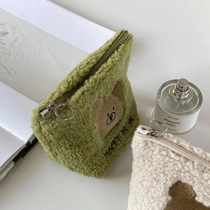 Macro view of teddy fleece texture and bear embroidery on this green makeup bag