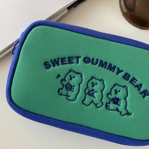 Detail of green canvas bag with blue zippers and embroidered sweet gummy bear cartoon