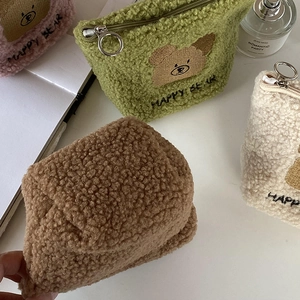 Macro detail of soft fleece teddy bear makeup bags with embroidered Happy Bear logo