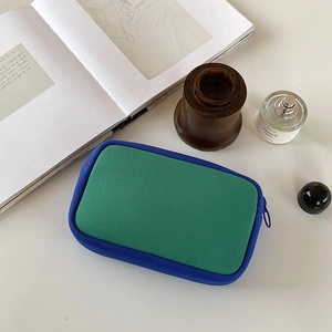 Detail of a dual-color cosmetic bag with green knit fabric and blue zipper trim