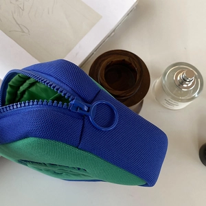 Detail view of contrast blue and green makeup bag with thick zipper and round metal ring
