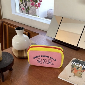 Detail of yellow canvas pouch with sweet gummy bear embroidery on a cozy wooden table