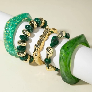 Green resin and gold metal beads 5-piece bracelet set stacked on a minimalist display