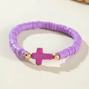 Détail d'un bracelet bohème en perles heishi violettes avec accents dorés et croix