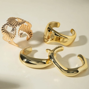 Set of four glossy gold open bangles with geometric textures and minimalist wavy designs