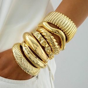 Gros plan de bracelets joncs dorés superposés avec designs martelés et torsadés élégants