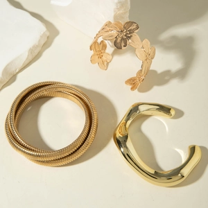 Détail de trois bracelets dorés vintage avec motifs floraux et textures ondulées