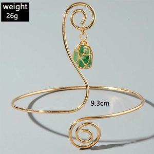 Detail view of adjustable gold-tone arm cuff with green gemstone pendant and size labels