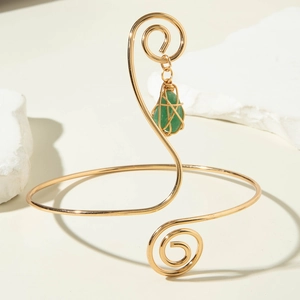 Detail of adjustable gold spiral arm cuff with a wire-wrapped green gemstone pendant