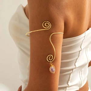 Detailed shot of golden arm cuff featuring spiral wire craft and a purple gemstone pendant