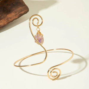 Detail of gold spiral wire arm cuff with a purple amethyst stone pendant wrap