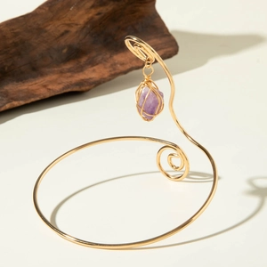 Detailed close-up of gold spiral upper arm cuff with a wrapped purple amethyst pendant