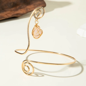 Detailed close-up of bohemian gold spiral armlet with wire-wrapped rose quartz pendant
