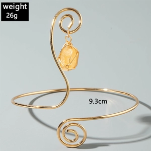 Detailed view of 26g golden spiral arm cuff featuring a wrapped yellow gemstone charm