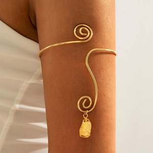 Detailed close-up of golden spiral upper arm cuff with natural yellow gemstone pendant