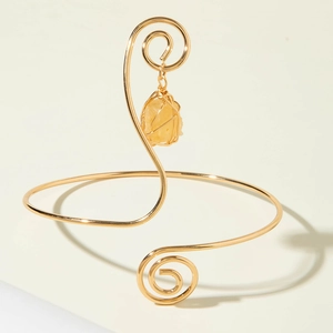 Bohemian gold spiral arm cuff featuring a natural yellow raw stone pendant charm