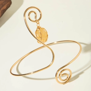 Detail of golden spiral arm cuff with a yellow gemstone pendant in boho style