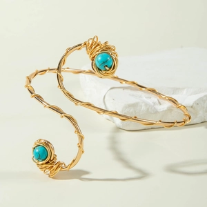 Close-up of golden spiral arm cuff with turquoise beads in a woven bird nest setting