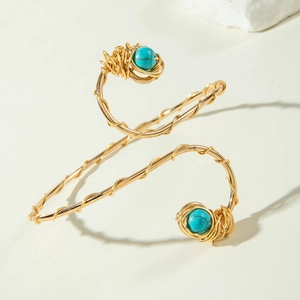 Bohemian spiral arm cuff in gold wire with turquoise beads on a minimalist background