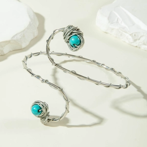 Detail of silver spiral upper arm cuff with turquoise beads on stone background