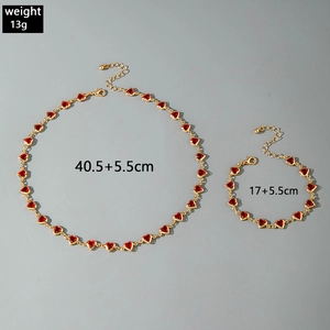 Flat lay of gold heart necklace and bracelet set with red enamel charms and lobster clasps