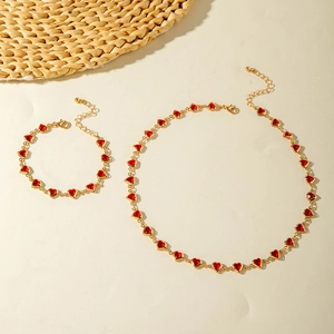 Detailed top view of gold necklace and bracelet set with elegant red heart pendants