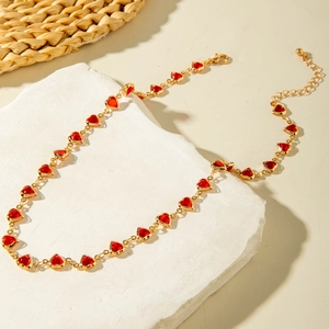 Macro detail of red heart pendant necklace with gold chain and lobster clasp closure
