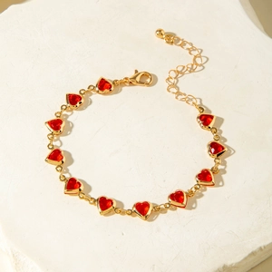 Detailed close-up of a gold chain necklace with vibrant red heart-shaped crystals