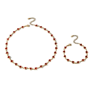 Elegant gold necklace and bracelet set featuring vibrant red heart-shaped crystals