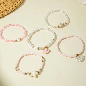 Ensemble de cinq bracelets en perles avec coquillages roses, étoiles de mer et perles marines