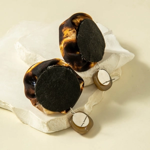 Macro detail of leopard print fabric flower earrings with brown resin pendants