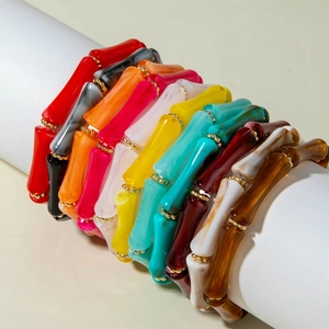 Dettaglio di bracciali colorati in acrilico stile bambù con distanziatori dorati in posa
