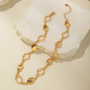 Detail of chunky gold chain necklace with hammered metal plates on stone texture
