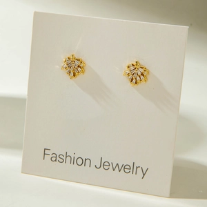 Macro shot of gold leaf-shaped stud earrings with sparkling zircon stones on display