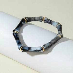 Dettaglio del bracciale in acrilico con trama marmo nero e distanziatori dorati