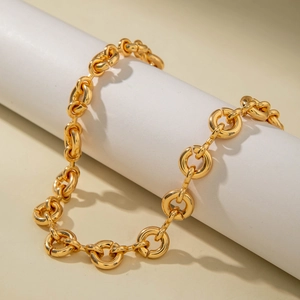 Detailed view of bold gold chunky chain necklace wrapped on a minimalist white prop
