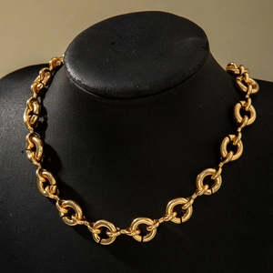 Detail showing thick gold metal link chain on a black jewelry display stand