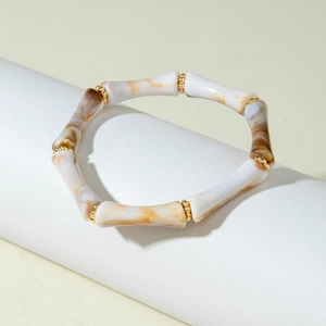 Dettaglio di perle in acrilico stile bambù con texture ambra marmorizzata e inserti oro