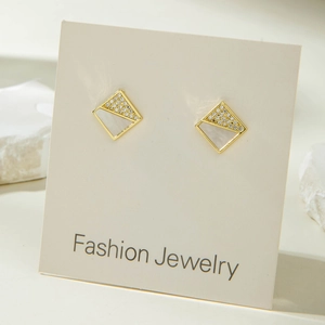 Detailed close-up of geometric diamond earrings with zircon pave and white mother of pearl