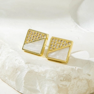 Macro shot of gold square earrings with inlaid cubic zirconia and pearl shell inlay